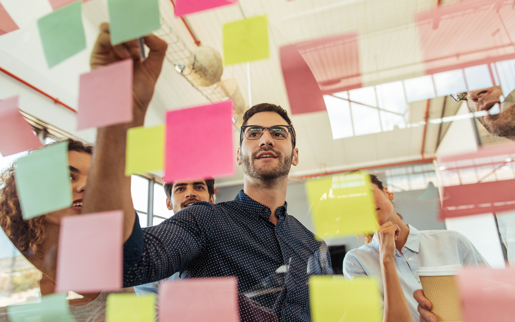 people putting postits on glass wall